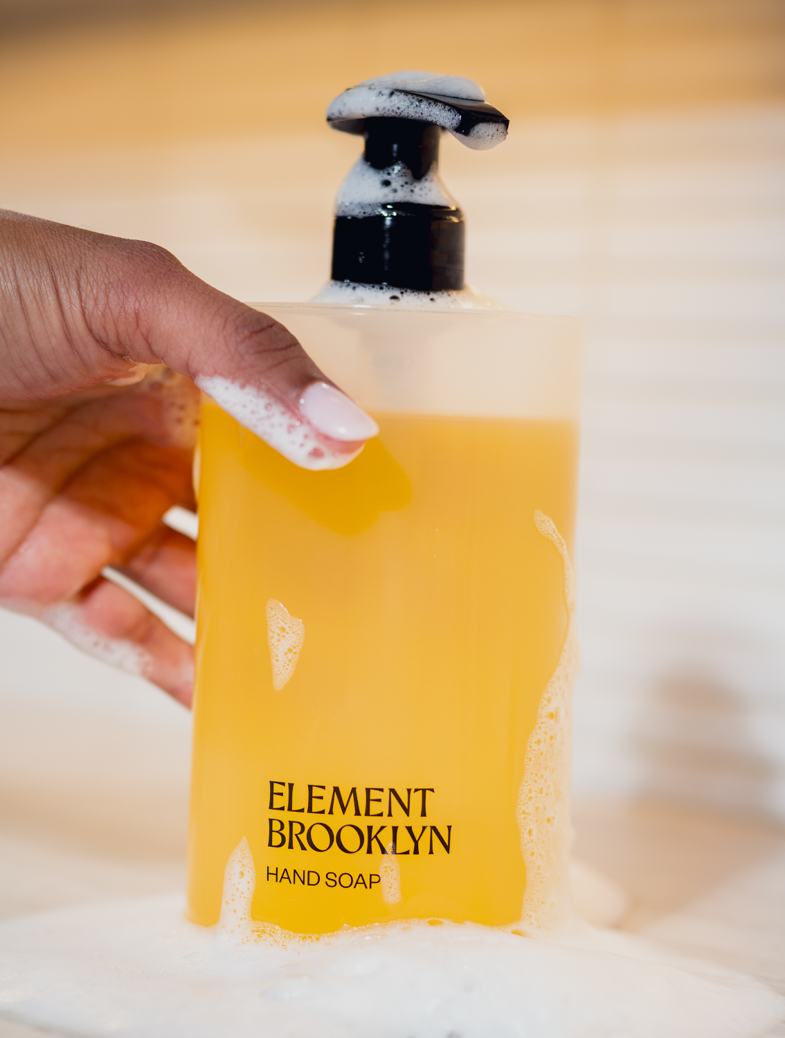Hands holding a bottle of Element Brooklyn liquid hand soap
